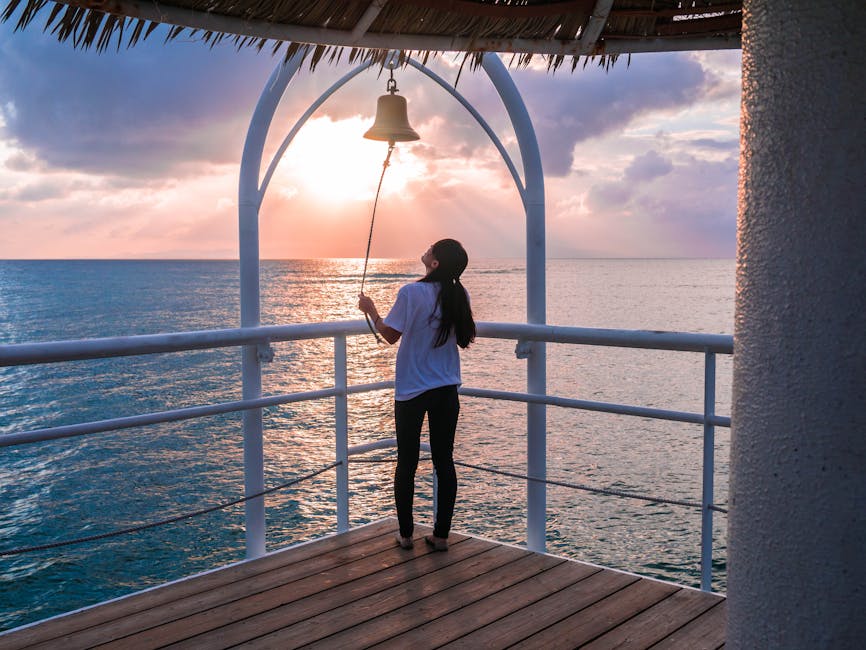 Woman in a tranquil yoga posture on a wooden deck by the water at sunrise